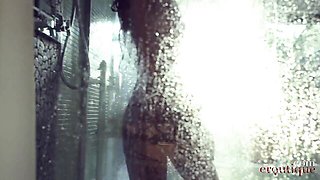 Katya Clover squats under showerhead on green tiled stall floor