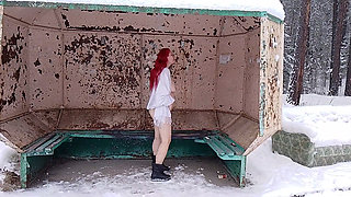A redheaded girl is playing with her body at a public bus stop in winter!